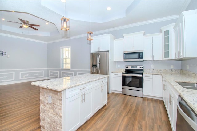 kitchen with a raised ceiling, appliances with stainless steel finishes, white cabinets, and decorative light fixtures