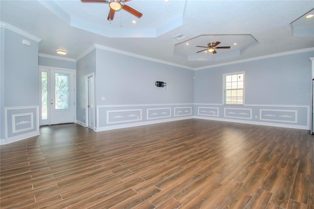 unfurnished living room with wood finished floors, visible vents, a ceiling fan, ornamental molding, and a raised ceiling