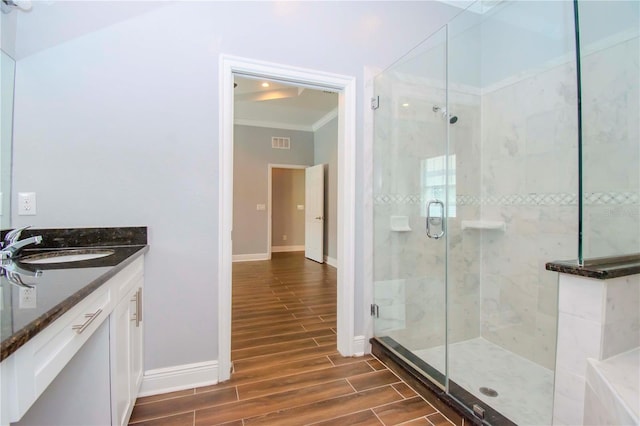 full bathroom featuring wood finish floors, visible vents, baseboards, ornamental molding, and a shower stall