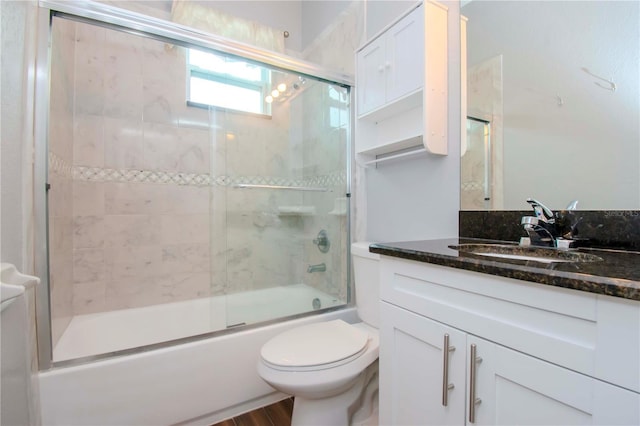 bathroom with enclosed tub / shower combo, vanity, and toilet