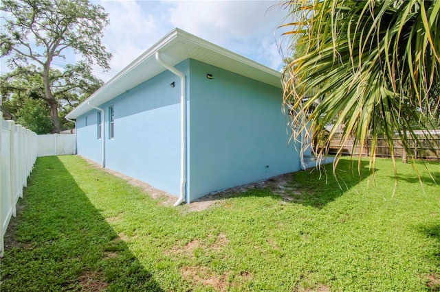 view of side of property featuring a fenced backyard, a yard, and stucco siding