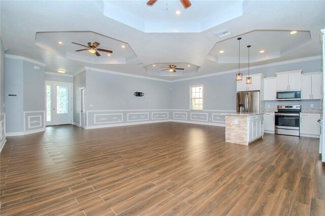 unfurnished living room with a tray ceiling, dark wood-type flooring, and plenty of natural light