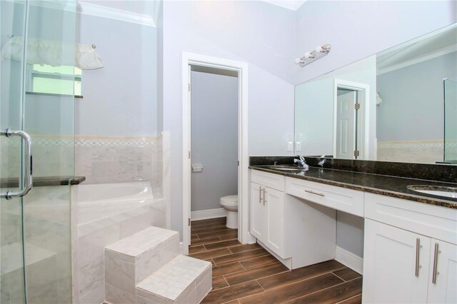 full bathroom featuring double vanity, toilet, crown molding, wood finish floors, and a sink