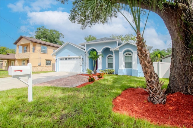 view of front of home featuring a garage, fence, driveway, stucco siding, and a front yard