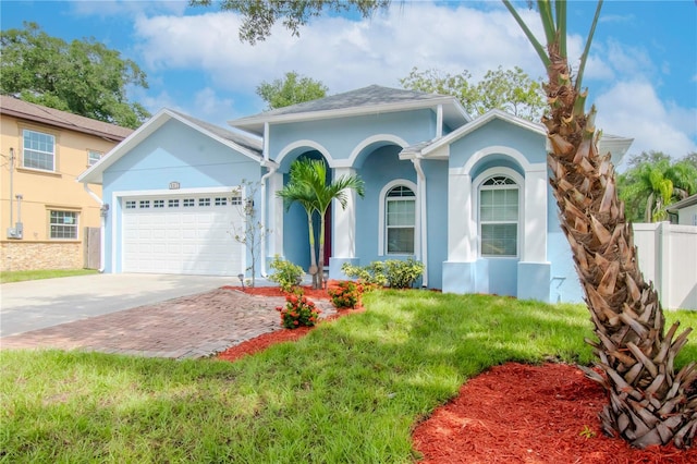 view of front of property featuring an attached garage, fence, concrete driveway, stucco siding, and a front yard