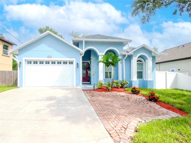 ranch-style house with a garage, fence, concrete driveway, and stucco siding