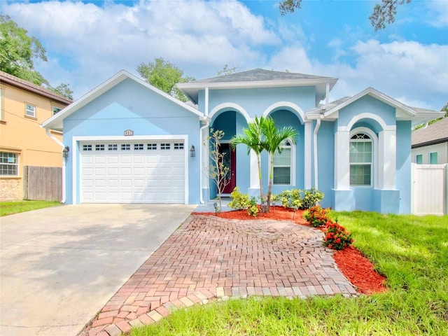 ranch-style home with an attached garage, driveway, fence, and stucco siding