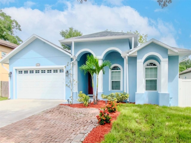 ranch-style home with concrete driveway, an attached garage, fence, and stucco siding