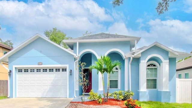 view of front of home featuring a garage, fence, driveway, and stucco siding