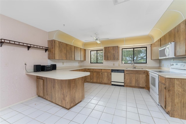 kitchen with light tile patterned flooring, sink, kitchen peninsula, white appliances, and ceiling fan