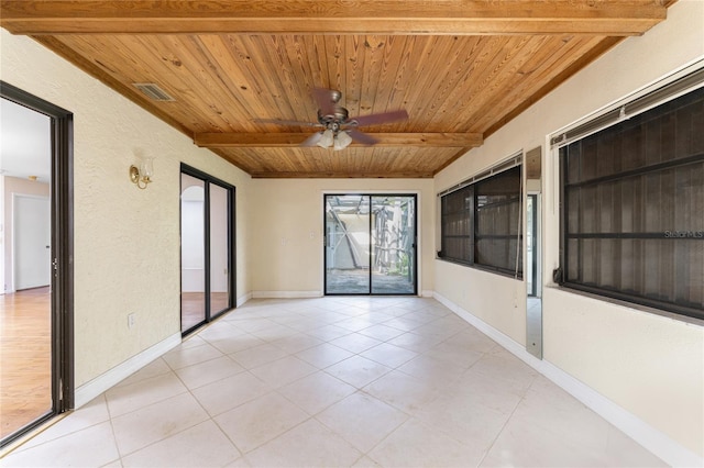 unfurnished room featuring wood ceiling, light tile patterned flooring, ceiling fan, and beamed ceiling