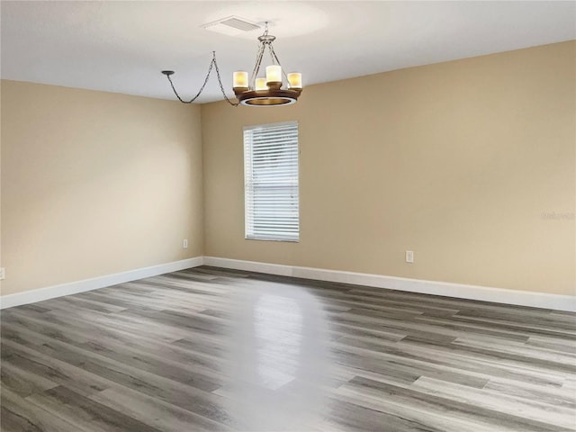 unfurnished room featuring wood-type flooring and an inviting chandelier