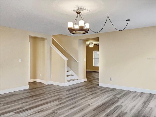 empty room with hardwood / wood-style floors and a notable chandelier