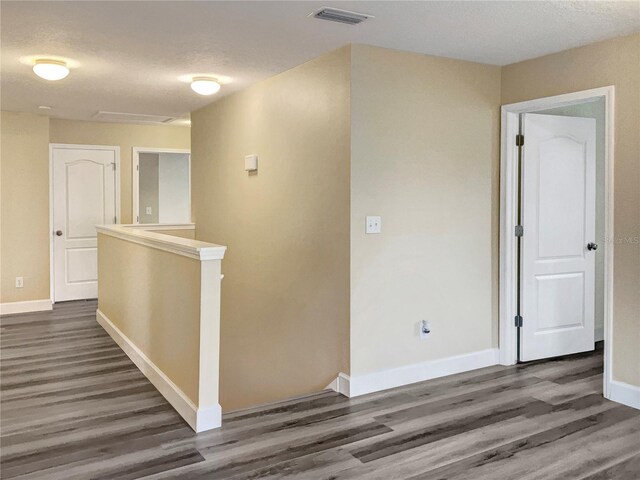 hall with a textured ceiling and dark wood-type flooring