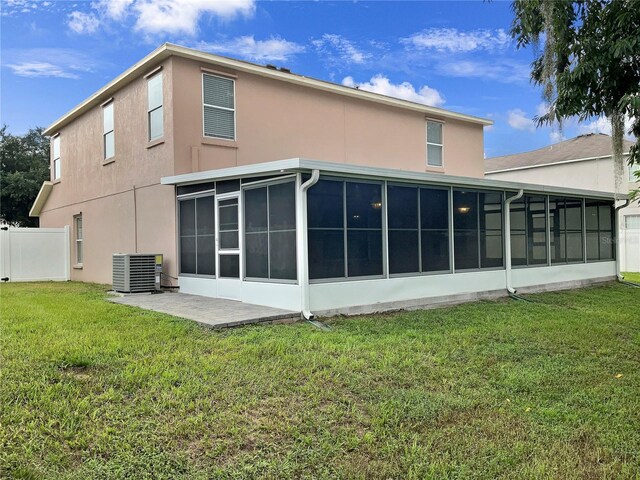 rear view of house with a lawn, a sunroom, and central AC