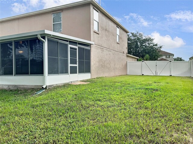 view of side of property with a sunroom and a yard