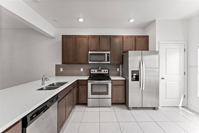 kitchen with decorative backsplash, light tile patterned floors, stainless steel appliances, dark brown cabinetry, and sink