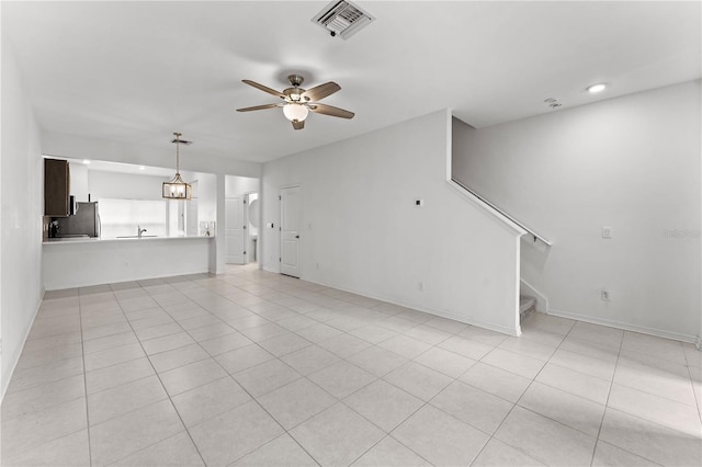 unfurnished living room with ceiling fan with notable chandelier, light tile patterned floors, and sink