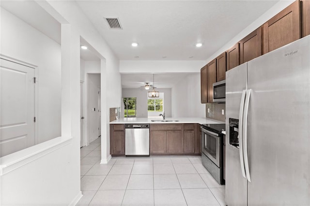 kitchen featuring appliances with stainless steel finishes, light tile patterned floors, sink, and ceiling fan