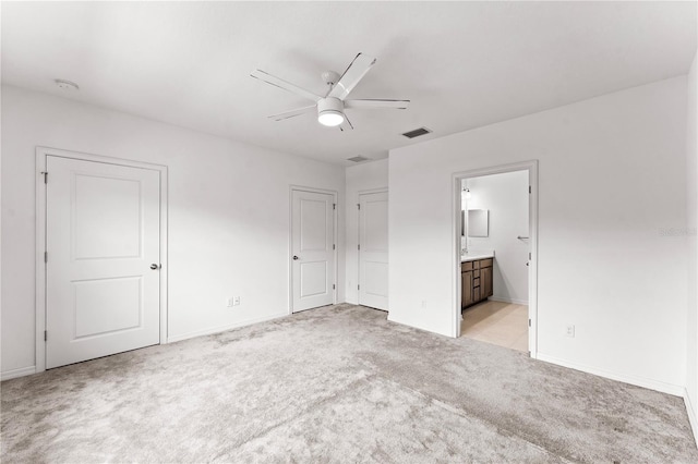 unfurnished bedroom featuring ensuite bath, ceiling fan, and light colored carpet