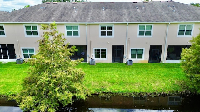 rear view of property featuring a lawn and central AC unit