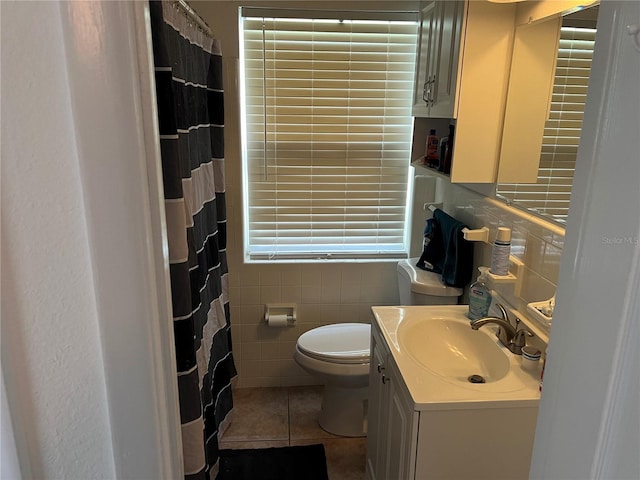 bathroom with vanity, toilet, tile walls, and tile patterned flooring