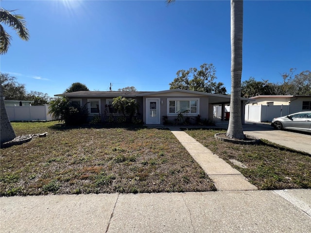 single story home featuring a carport, fence, driveway, and a front lawn