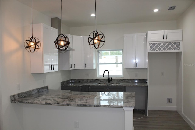 kitchen featuring dark stone counters, white cabinetry, sink, and pendant lighting