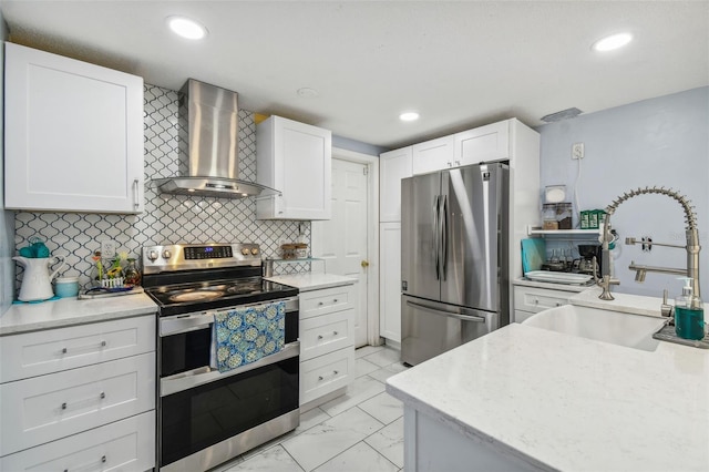 kitchen with stainless steel appliances, white cabinetry, wall chimney exhaust hood, and sink