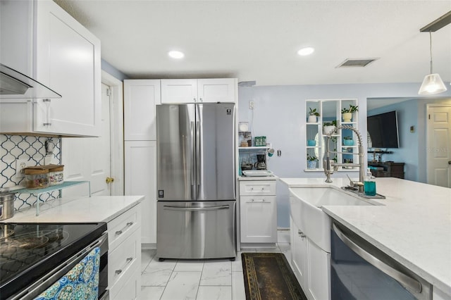 kitchen featuring stainless steel fridge, wall chimney range hood, dishwasher, white cabinetry, and hanging light fixtures