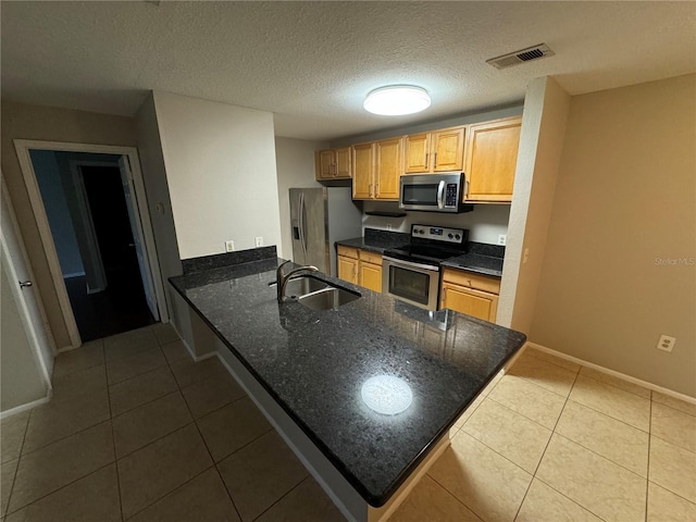 kitchen featuring a textured ceiling, stainless steel appliances, sink, and kitchen peninsula