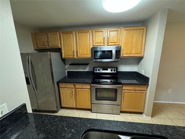 kitchen featuring a textured ceiling, appliances with stainless steel finishes, and light tile patterned flooring