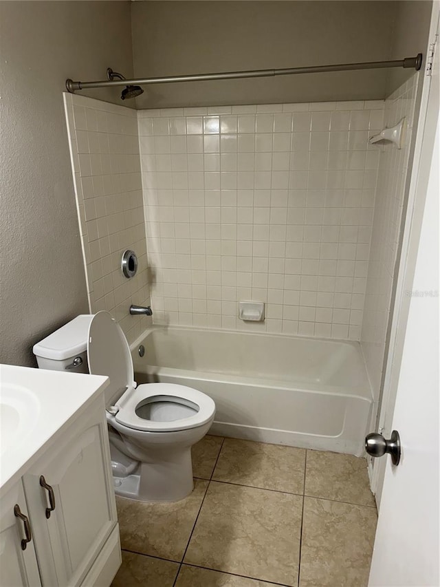 full bathroom with tile patterned flooring, tiled shower / bath combo, vanity, and toilet