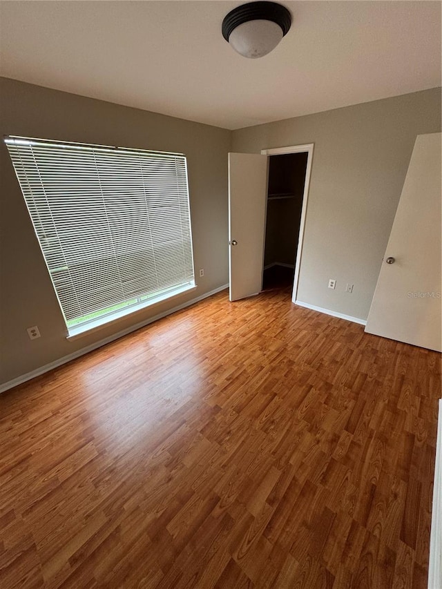 unfurnished bedroom with wood-type flooring and a walk in closet