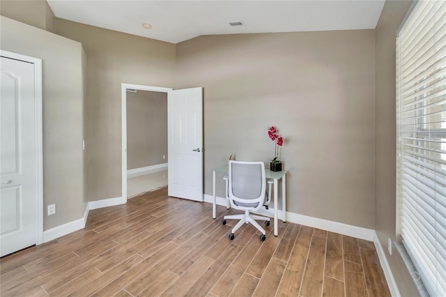 unfurnished office featuring light hardwood / wood-style flooring and vaulted ceiling