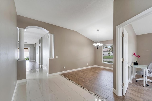 interior space featuring lofted ceiling, light hardwood / wood-style floors, a chandelier, and ornate columns