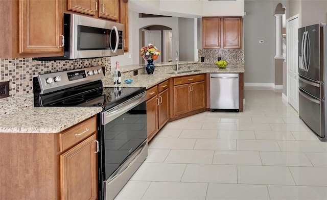 12739 Standbridge Dr, Riverview, FL 33579 - kitchen with stainless steel appliances, brown cabinetry, a sink, and backsplash