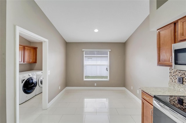 interior space featuring washer and clothes dryer, decorative backsplash, light tile patterned floors, and stainless steel appliances