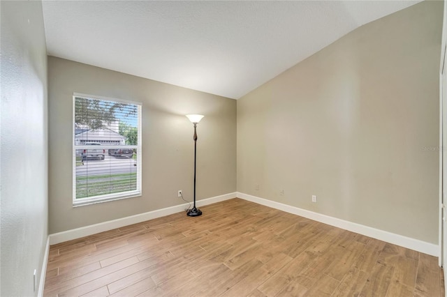 unfurnished room featuring light hardwood / wood-style floors and lofted ceiling