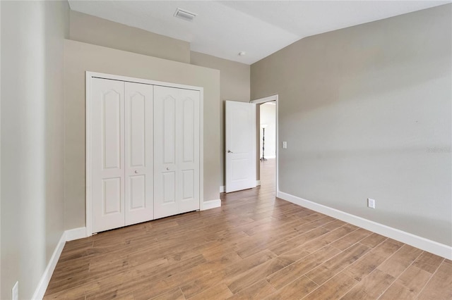 unfurnished bedroom with a closet, vaulted ceiling, and light hardwood / wood-style floors