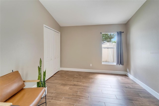 unfurnished room with light wood-type flooring and lofted ceiling