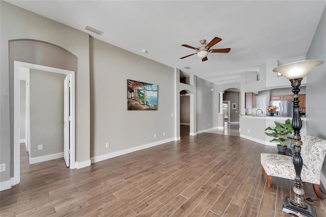 unfurnished living room featuring ceiling fan, hardwood / wood-style flooring, and sink