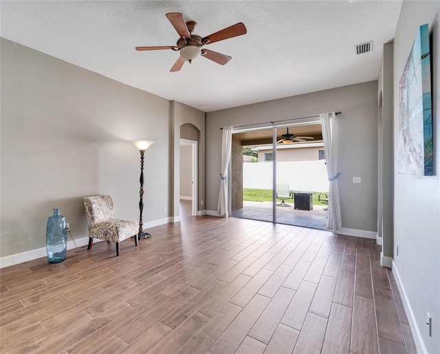 unfurnished room with a textured ceiling, ceiling fan, and light hardwood / wood-style flooring