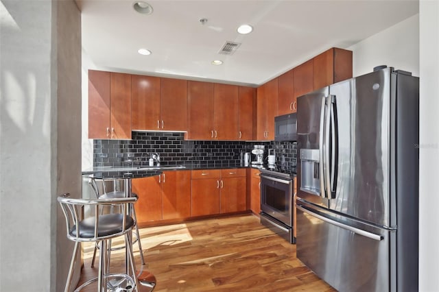 777 N Ashley Dr Unit 1606, Tampa, FL 33602 - kitchen with appliances with stainless steel finishes, dark countertops, wood finished floors, backsplash, and brown cabinets