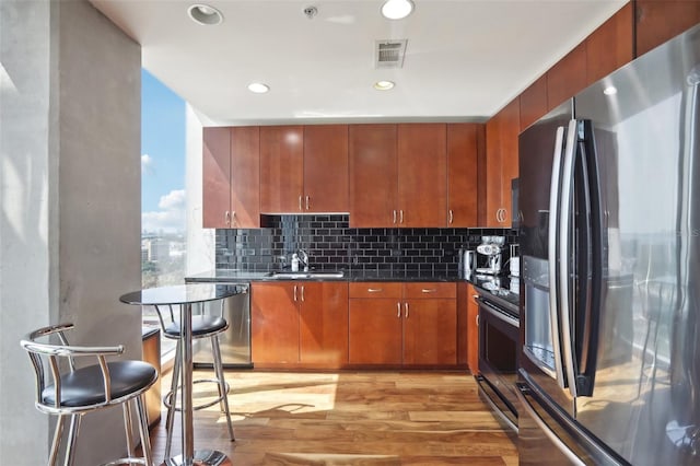 kitchen featuring light wood-type flooring, decorative backsplash, sink, and stainless steel appliances