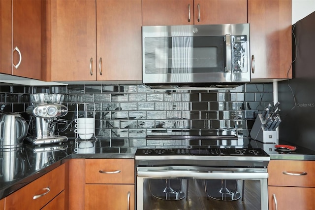 kitchen with dark stone countertops, appliances with stainless steel finishes, and tasteful backsplash