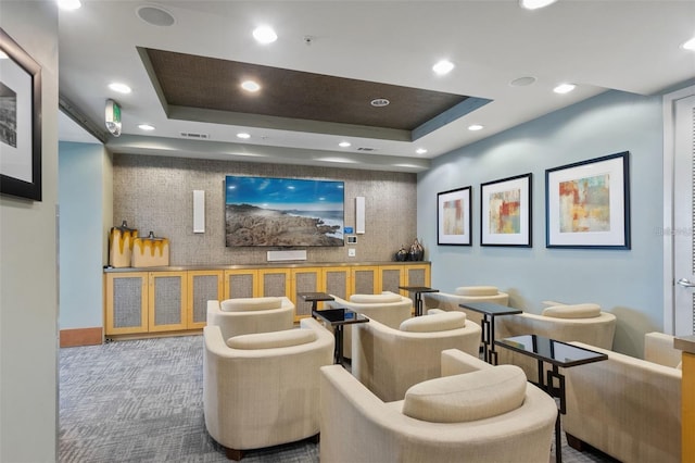 cinema room featuring a tray ceiling and carpet flooring