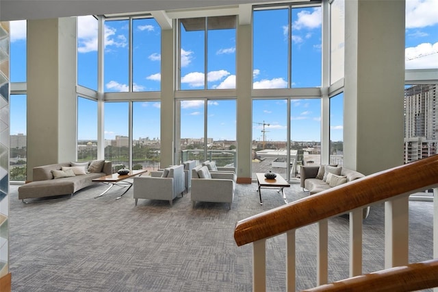 living room with carpet floors, a high ceiling, and a wall of windows