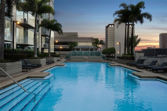 pool at dusk featuring a patio and pool water feature