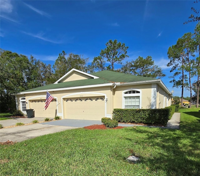 ranch-style home featuring driveway, an attached garage, a front yard, and stucco siding